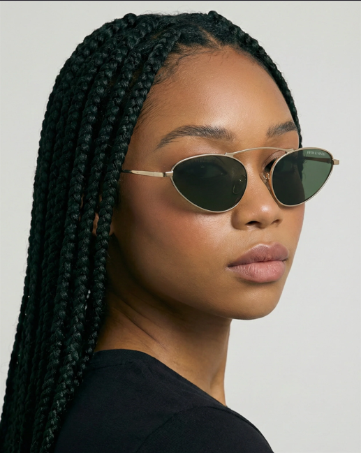 Person wearing sunglasses with braided hair against a plain background