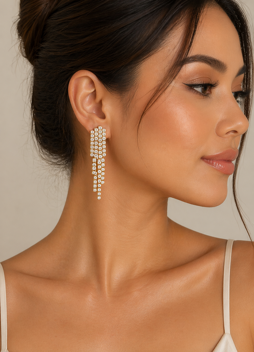 Close-up of a woman wearing a pair of dangling earrings with a neutral background perfect for Wedding and Special occasions