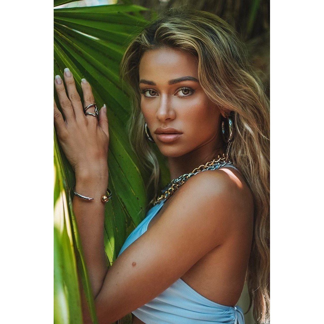 Model wearing silver tubular hoop earrings with a sleek polished finish in an elegant outdoor setting